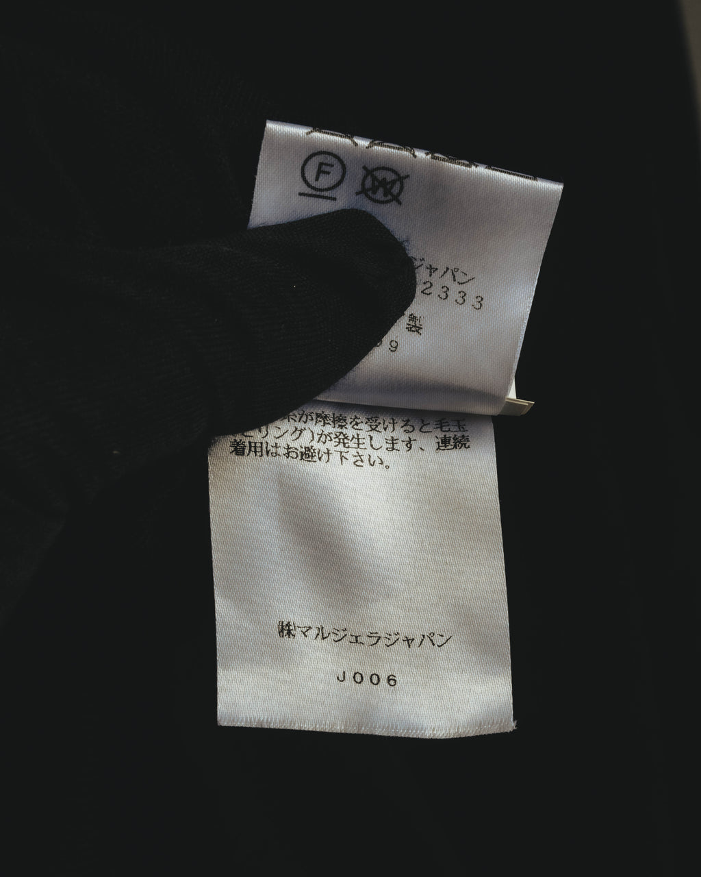 新JIS系の洗濯表示と、国内表示者「株式会社マルジェラジャパン」の表記を確認できる内タグのカット。品番表記も写っています。