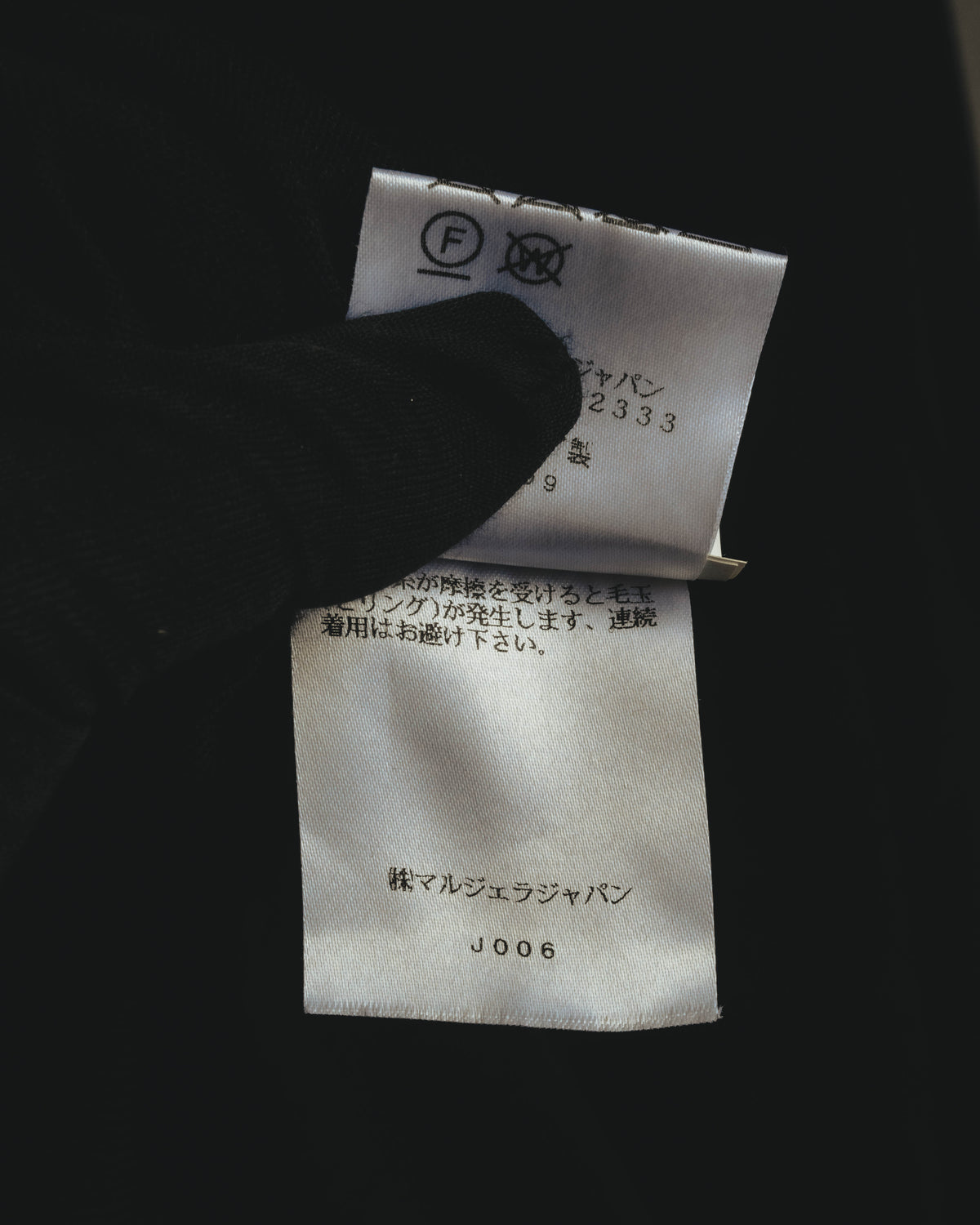 新JIS系の洗濯表示と、国内表示者「株式会社マルジェラジャパン」の表記を確認できる内タグのカット。品番表記も写っています。
