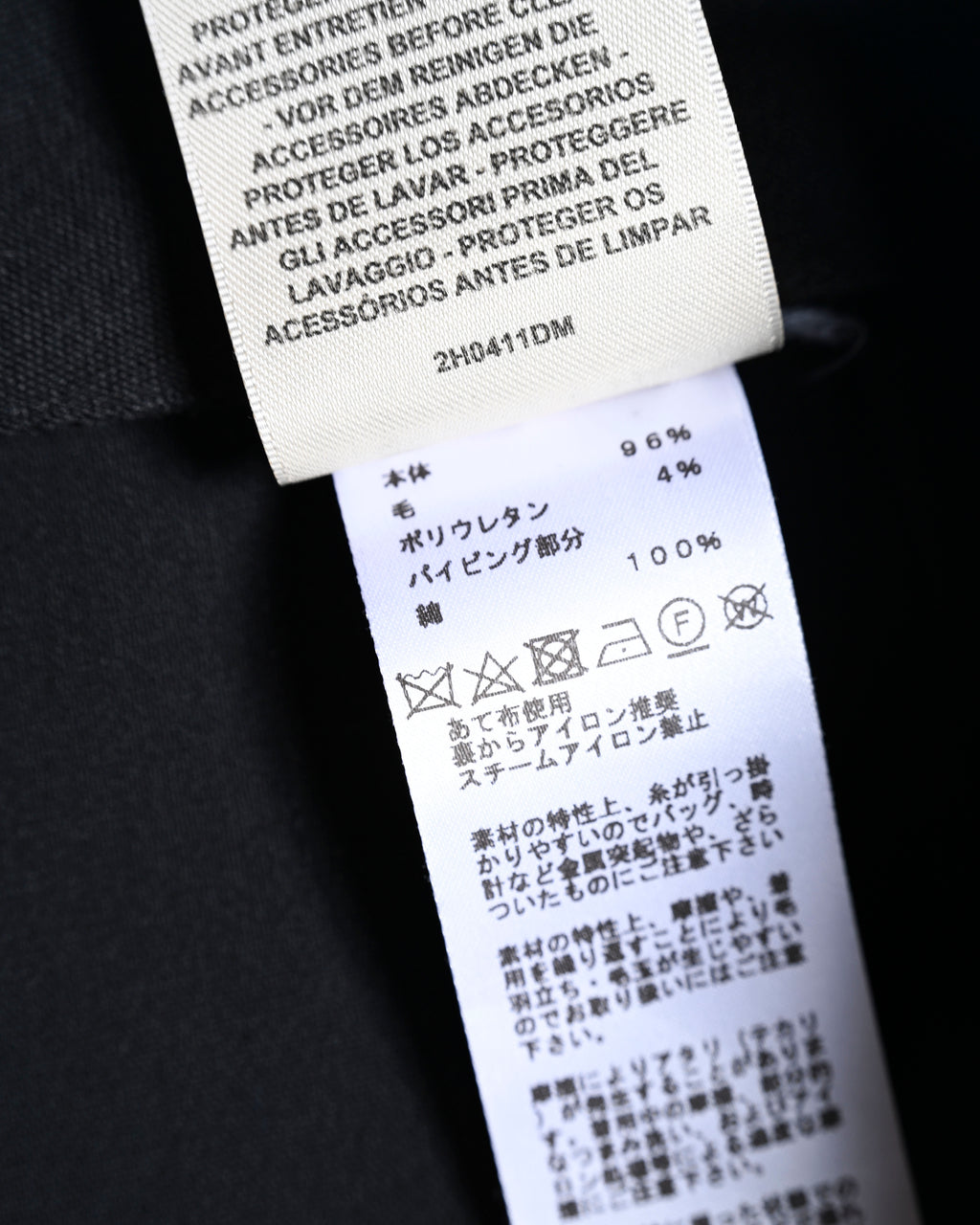 内側の多言語ケアラベルを写したカット。品番2H0411DM、本体ヴァージンウール96パーセント・ポリウレタン4パーセント、パイピング部分コットン100パーセントの表記を確認できます。