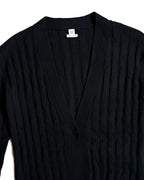 首元のHERMÈS PARISタグと、胸元へすっきりと落ちる深めのVネックを捉えたカット。縦方向の立体的な編み柄と、前立てを一つのボタンで留めるミニマルな構造が確認できます。