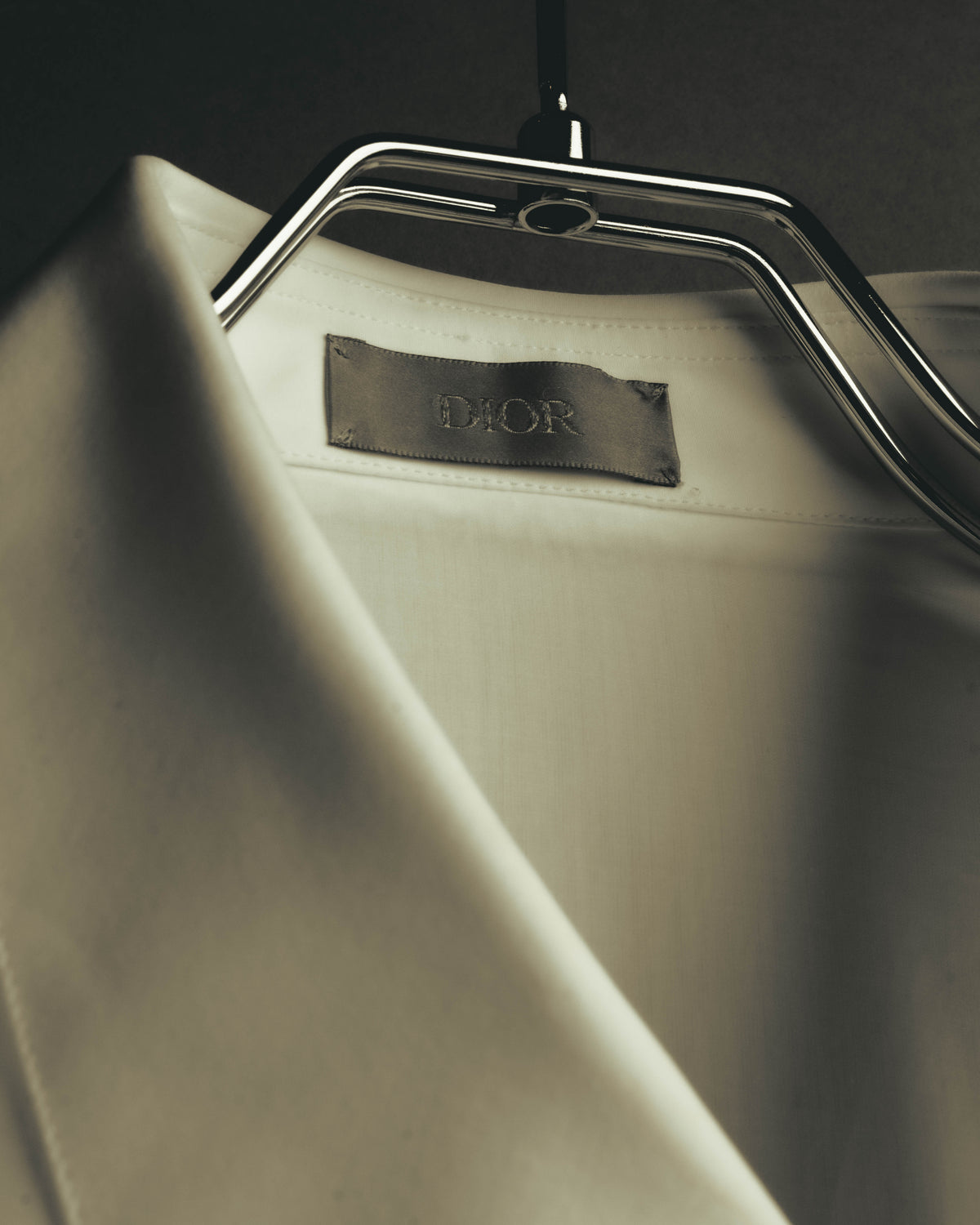 襟元に配された、全大文字でDIORと表記されたブランドタグのクローズアップ。旧来のDior Hommeではないタグ表記を確認できるカットです。