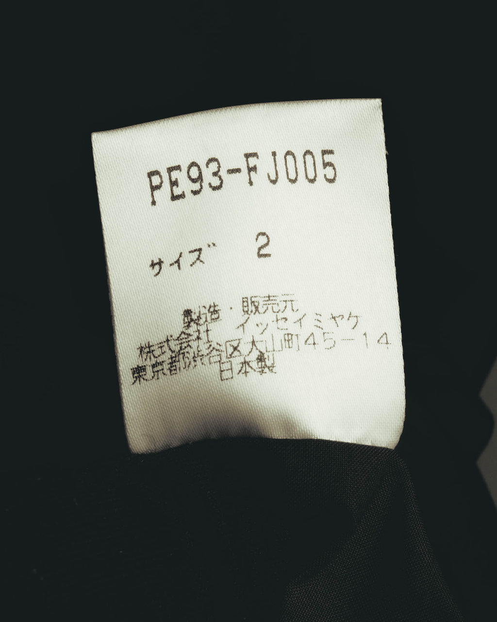 品番「PE93-FJ005」、サイズ2、ポリエステル100％、株式会社イッセイミヤケの旧所在地表記および日本製表記を確認できる品質表示タグ。
