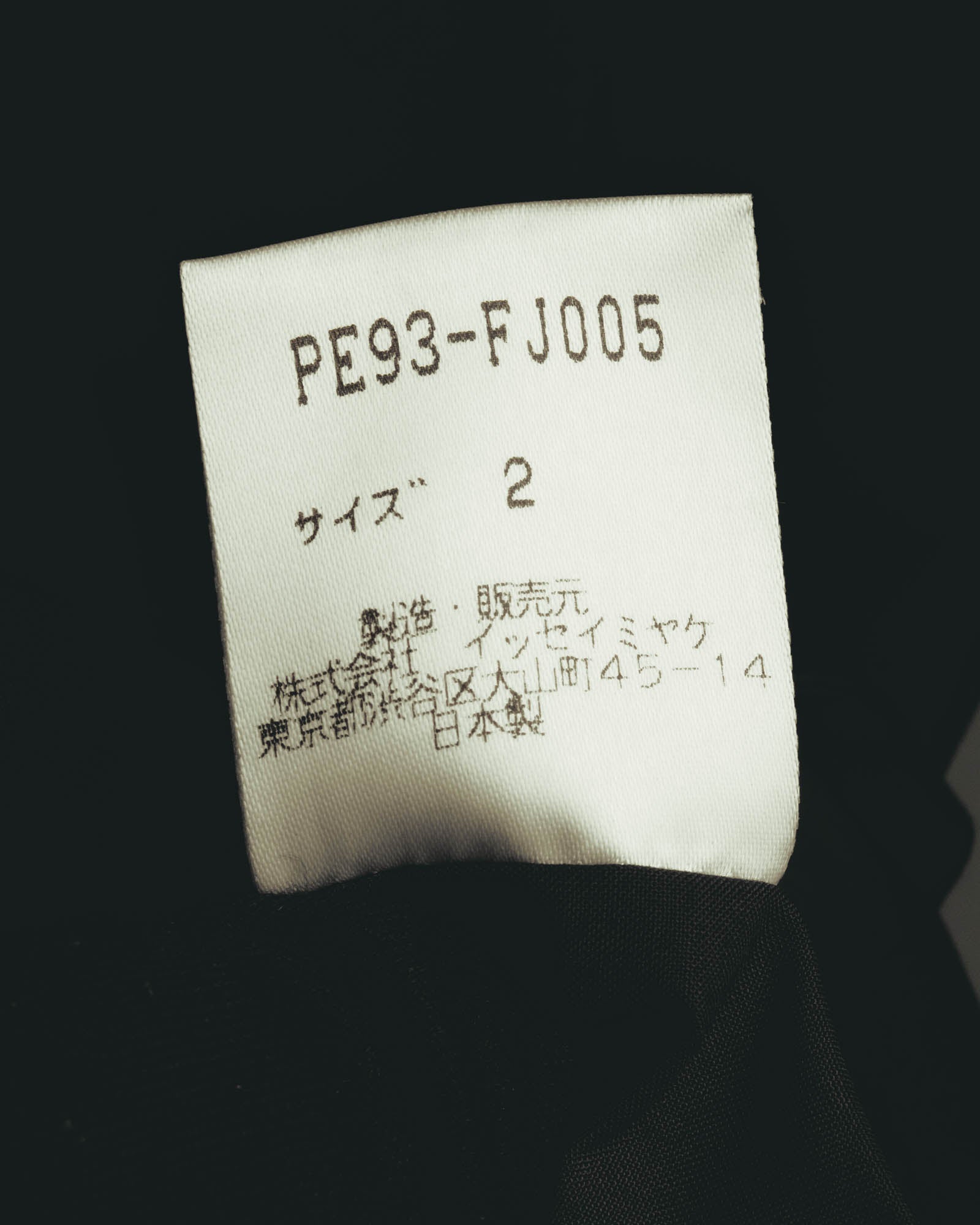 品番「PE93-FJ005」、サイズ2、ポリエステル100％、株式会社イッセイミヤケの旧所在地表記および日本製表記を確認できる品質表示タグ。