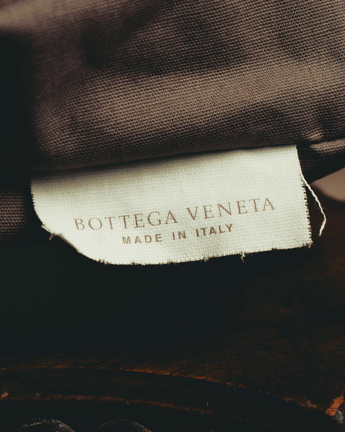 ブラウン系の内装生地に配された、BOTTEGA VENETAとMADE IN ITALYの二段表記を確認できる生成り色の織物タグ。