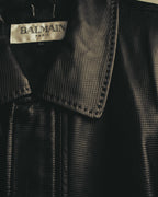 「BALMAIN PARIS」表記とLLサイズ表記を確認できる首元のタグカット。周囲には細かな格子状のエンボス加工を施したブラックレザーと、襟の縁の編み込み状トリミングが写っています。