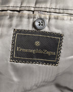 滑らかなグレー系の総裏地に配された、円形のZ意匠を持つErmenegildo Zegna表記の服地ネーム。内ポケット上部の4つ穴ボタンと、ネーム周囲のジグザグステッチも確認できるカット。