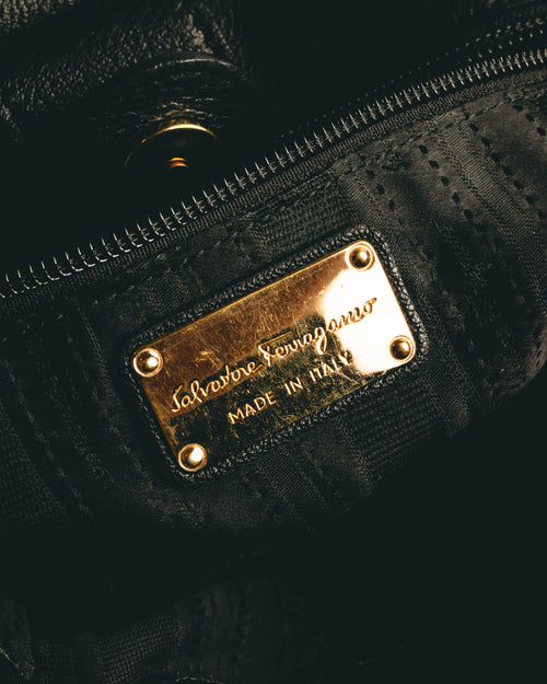 ブラックを基調とした柄織りライニングに配された内側の金属プレート。筆記体の Salvatore Ferragamo ロゴと MADE IN ITALY の刻印を確認できるカット。