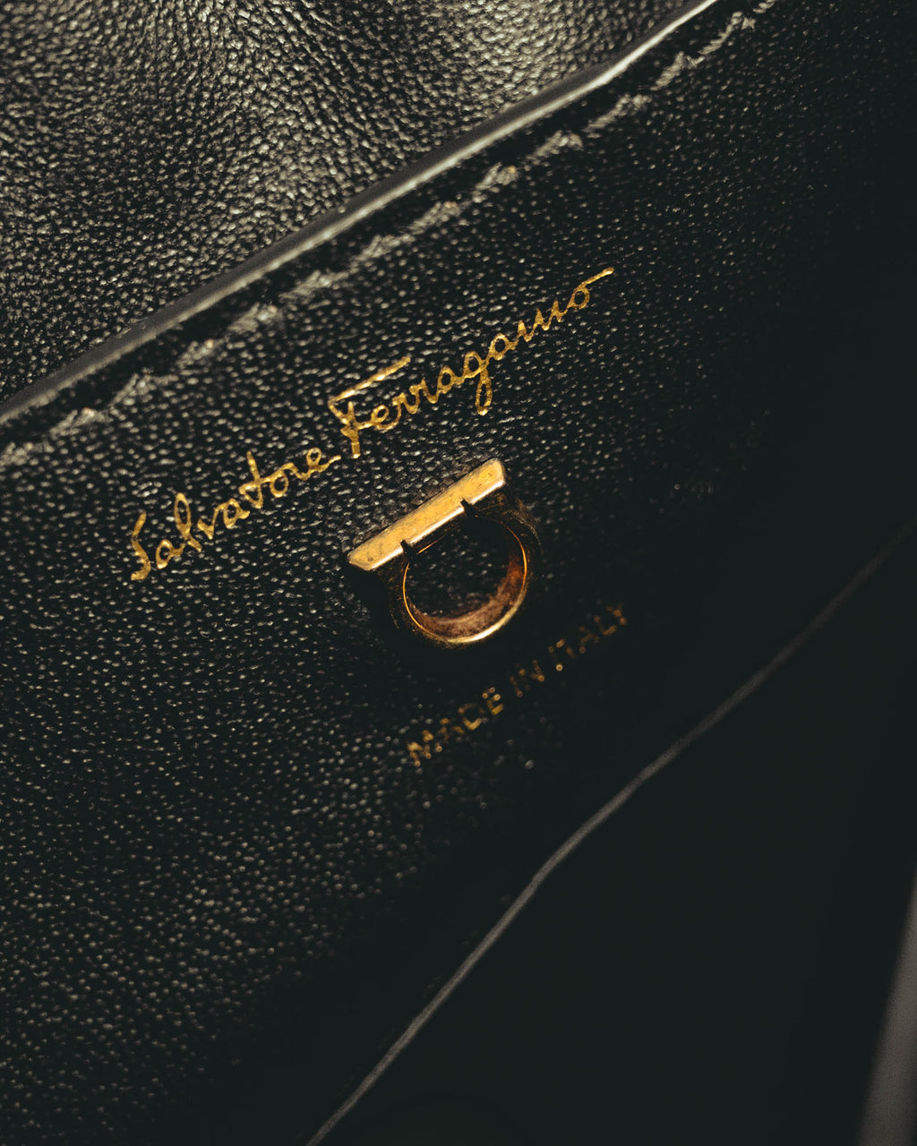 ブラックの内装に施された旧筆記体のSalvatore Ferragamoゴールド箔押しと、ショルダーストラップ用Dリングを捉えたディテールカット。