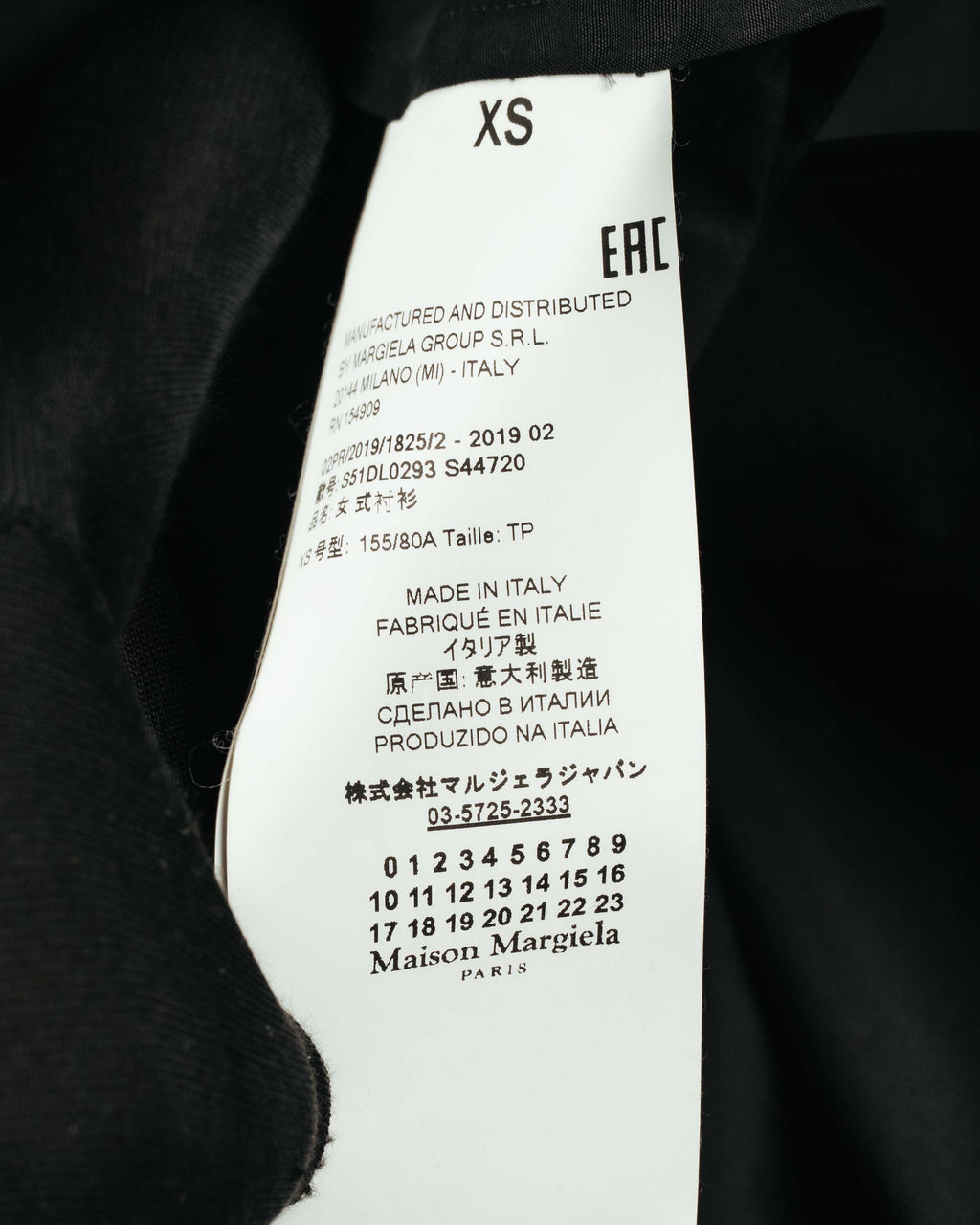 ネック内側に配されたカレンダータグと品質表示タグのクローズアップ。サイズ表記XS、ウィメンズコレクションを示す「1」の選択、および2019 02のシーズンコードを確認できるカット。