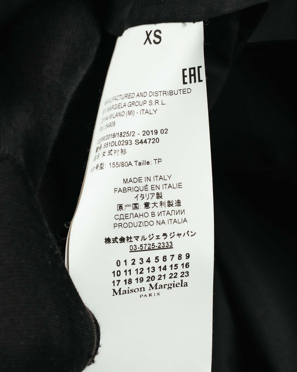 ネック内側に配されたカレンダータグと品質表示タグのクローズアップ。サイズ表記XS、ウィメンズコレクションを示す「1」の選択、および2019 02のシーズンコードを確認できるカット。