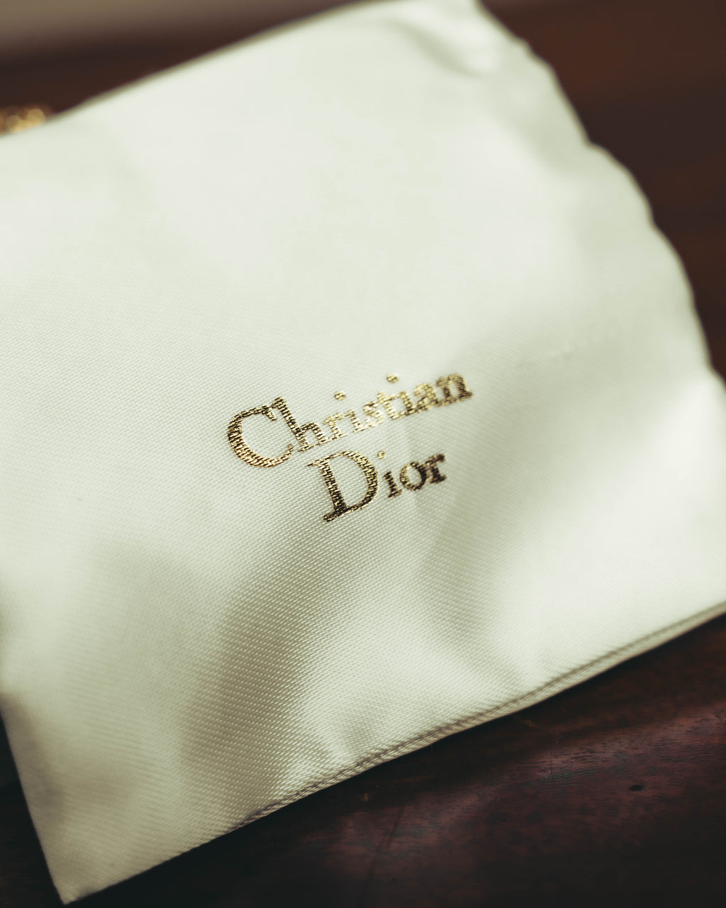 Christian Diorのロゴ表記を配した、付属のサテン調ポーチを写したカット。保管用付属品の仕様を確認できます。