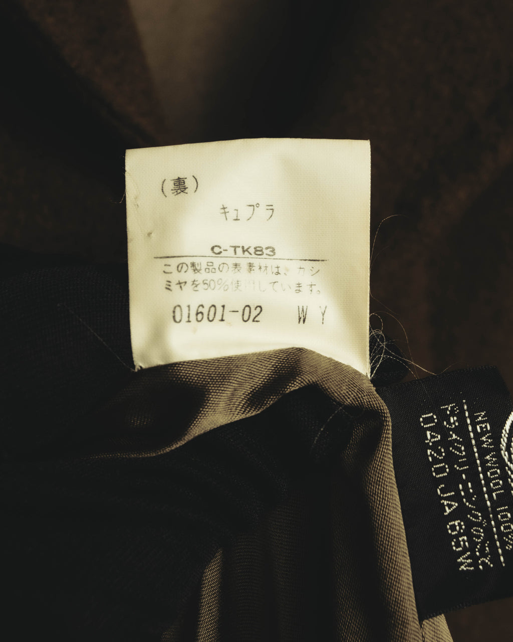 キュプラ裏地と、表素材にカシミヤ50%を使用していることを記した品質表示タグのクローズアップ。