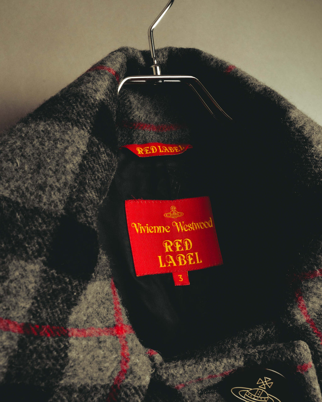 首元の内側に配されたVivienne Westwood RED LABELのブランドタグと、サイズ「3」表記を確認できるタグカット。ブラックの裏地とグレー×レッドのチェック柄もあわせて写しています。