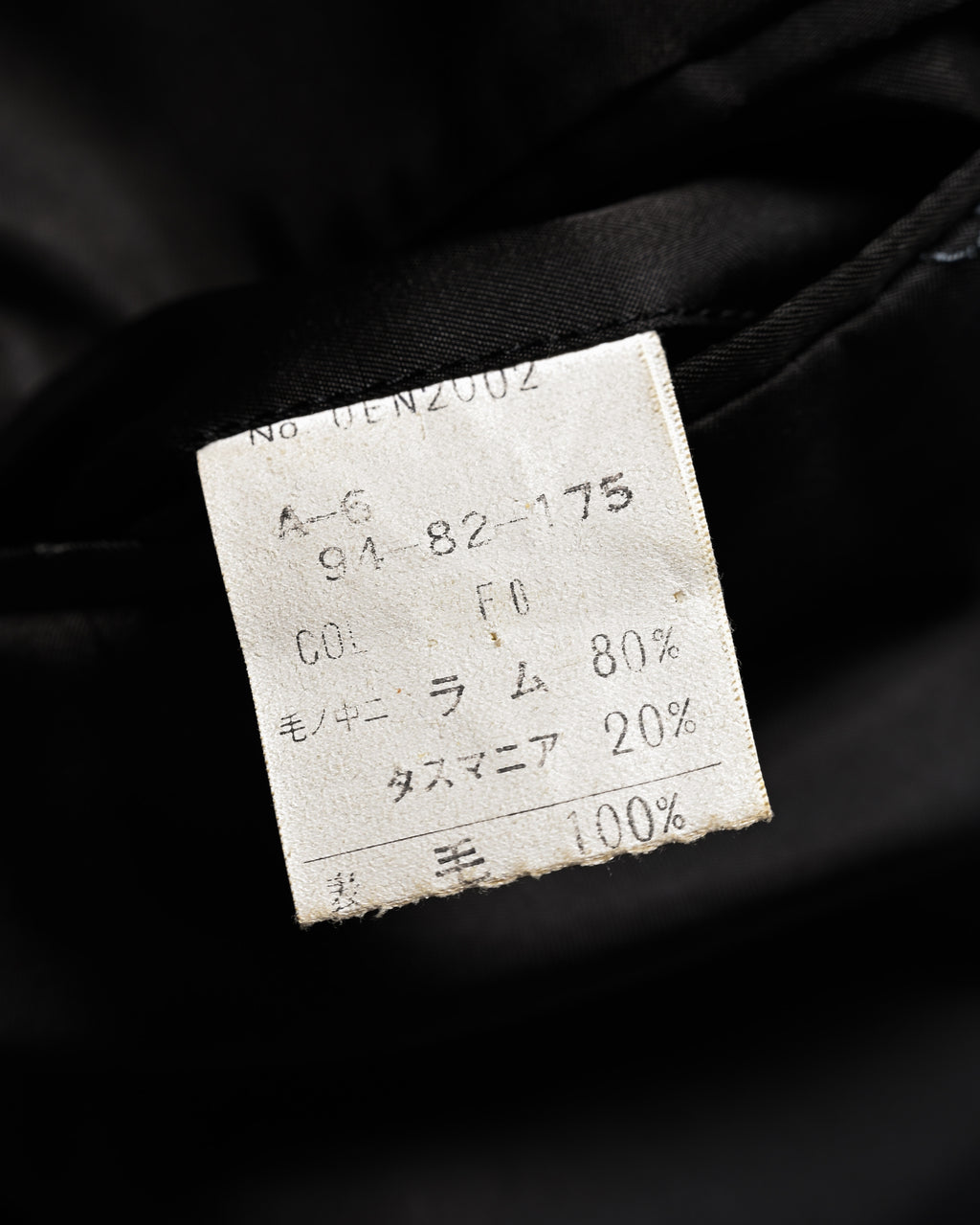 内側の品質表示タグ。毛100%のうちラム80%、タスマニア20%と、表記サイズA-6（胸囲91／胴囲82／身長175）が確認できるカット。