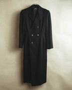 6つのボタンを配したダブルブレストと端正なノッチドラペルが確認できる前面全体。身頃から裾まで続く長いストレートラインがマキシ丈の輪郭を示しています。